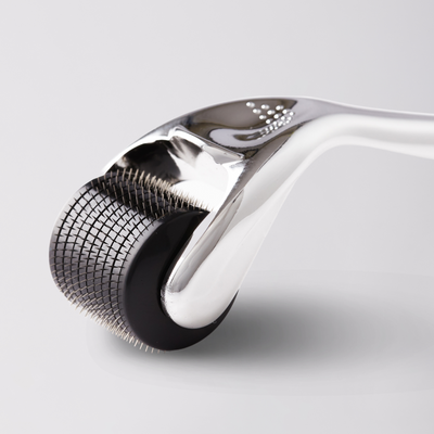 Close-up of a derma roller with metallic head on a light gray background